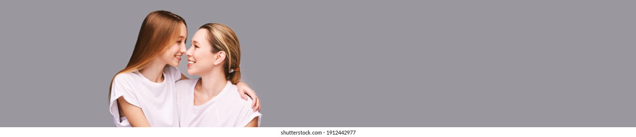 Mother And Daughter Studio Portrait. Grey Background. Smiling People. Two Female Person Family. Friends Hug. Communication Adult. Copyspace. Close Noses. Happy Woman And Girl