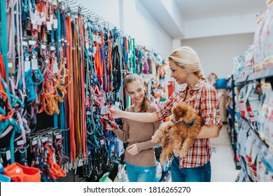 Mother and daughter with their poodle puppy in pet shop.