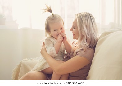 Mother and daughter toddler playing, kissing, hugging and smiling, enjoy at the sofa, spending time at home. Moments of tenderness . Happy loving family. Good time at home. Family single mother