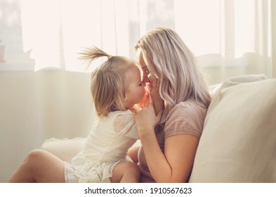 Mother and  daughter toddler playing, kissing, hugging  and smiling, enjoy at the sofa, spending time at home. Moments of tenderness . Happy loving family. Good time at home. Family single mother - Shutterstock ID 1910567623