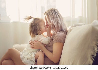 Mother and daughter toddler playing, kissing, hugging and smiling, enjoy at the sofa, spending time at home. Moments of tenderness . Happy loving family. Good time at home. Family single mother