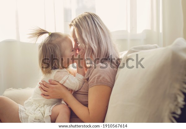 Mother and  daughter toddler playing, kissing,
hugging  and smiling, enjoy at the sofa, spending time at home.
Moments of tenderness . Happy loving family. Good time at home.
Family single mother