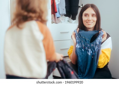 Mother And Daughter Trying On Clothes From The Closet Drawers. Child Helping Mom Ordering Garments After Playing Dress Up
