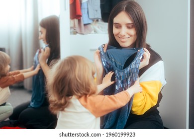 Mother And Daughter Trying On Clothes From The Closet Drawers. Child Helping Mom Ordering Garments After Playing Dress Up
