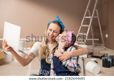 Mother and daughter using computer, making video call, greeting friend, having fun online modern apps little cute girl gives kiss to woman.
