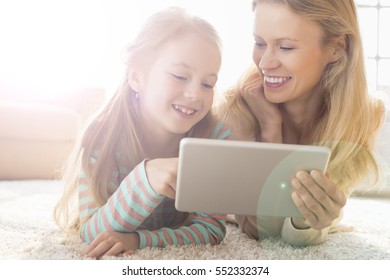 Mutter und Tochter, die digitale Tablette zu Hause auf dem Fußboden benutzt
