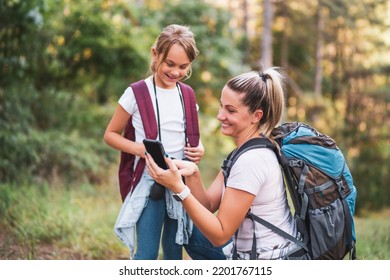 Mother And Daughter Using Map On Mobile Phone And Enjoy Hiking Together.