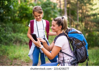 Mother And Daughter Using Map On Mobile Phone And Enjoy Hiking Together.