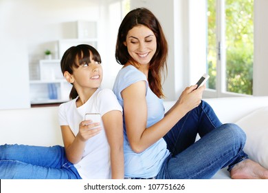 Mother And Daughter Using Mobile Phone At Home