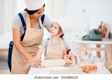 Mother and daughter using a rolling pin together in the kitchen - Powered by Shutterstock