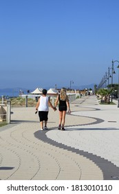 Mother and daughter walk along the promenade of Ardore in Calabria. Walking by holding hands. Two women filmed from behind as they walk. Two people on the seafront. Original corrugated flooring - wave