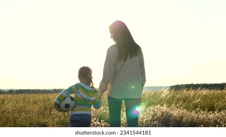 mother daughter walked hand hand, while girl happily walked alongside soccer ball. joyful smile her face, child enjoyed company mother. Together fulfilled childhood dream strolling across football - Powered by Shutterstock