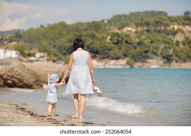 Mother And Daughter Walking Away On Beach