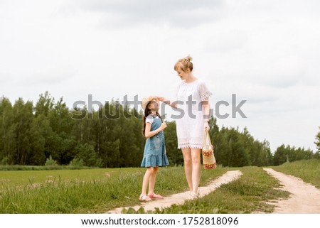 mother and daughter walking in the forest and holding hands.walk along the path. field and nature. Wicker basket. maternal love, happy childhood