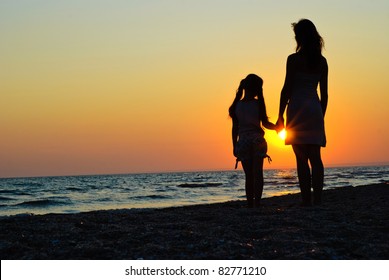 Mother And Daughter Walking On The Beach