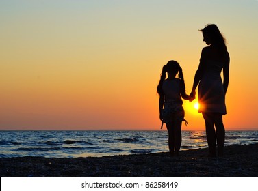 Mother And Daughter Walking On The Beach