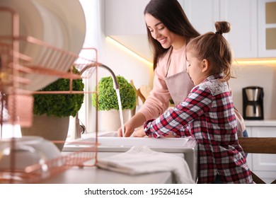 Mother and daughter washing dishes together in kitchen at home - Powered by Shutterstock