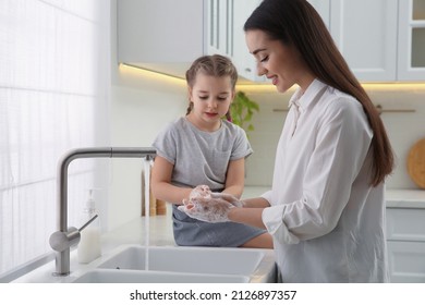 Mother and daughter washing hands with liquid soap in kitchen - Powered by Shutterstock