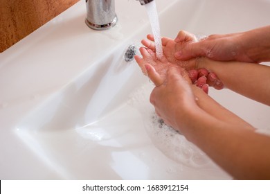 Mother and daughter washing hands with water and soap - Powered by Shutterstock