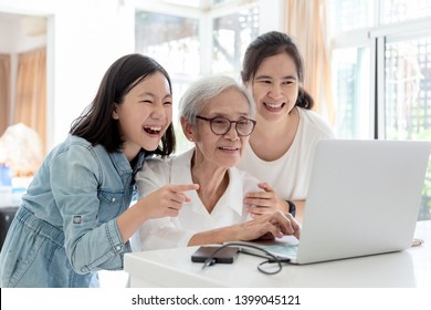 Mother And Daughter Watching Something Interesting With Grandmother,happy Smiling Asian Senior Woman While Her Daughter And Granddaughter Using Laptop Computer At Home,concept Family,technology