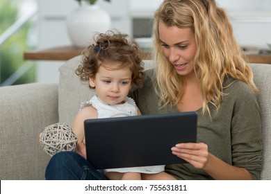 Mother And Daughter Watching Tv On Tablet