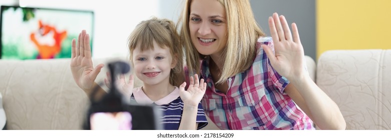 Mother And Daughter Wave Hello On Video, Videocamera Set On Tripod