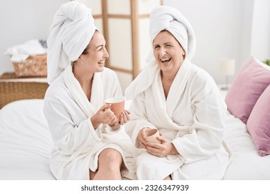 Mother and daughter wearing bathrobe drinking coffee at bedroom - Powered by Shutterstock