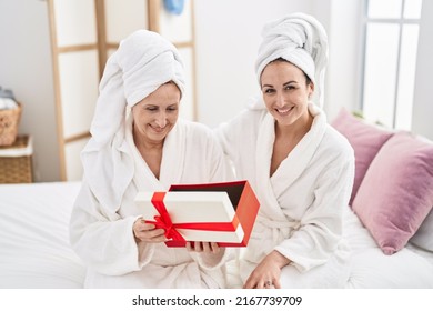 Mother And Daughter Wearing Bathrobe Surprise With Gift At Bedroom