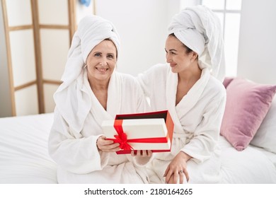 Mother And Daughter Wearing Bathrobe Surprise With Gift At Bedroom