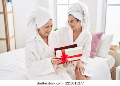 Mother And Daughter Wearing Bathrobe Surprise With Gift At Bedroom