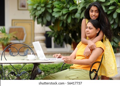 Mother and daughter working on laptop in outdoors