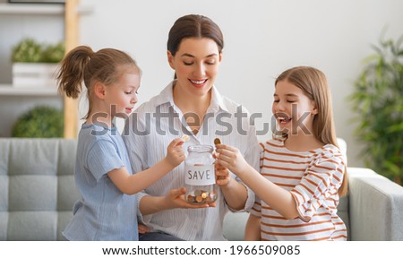 Mother and daughters are holding moneybox, girl putting coin.  moneybox, girl putting coin. 