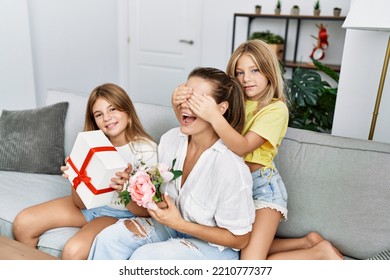 Mother And Daughters Smiling Confident Suprise With Gift And Flowers At Home