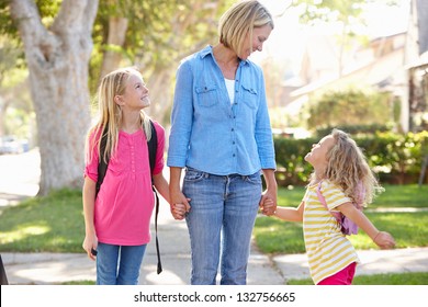 Mother And Daughters Walking To School On Suburban Street