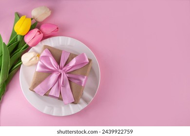 Mother day table setting background. Pink Mother's day border flat lay for brunch, lunch, dinner menu, invitation mockup. Beautiful table setting with golden cutlery, plate, tulip flowers and gift box