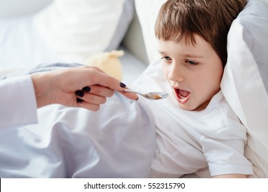 Mother Or Doctor Giving Sick Child A Syrup Medicine