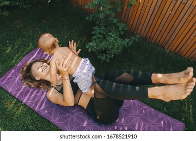 Mother doing baby yoga for her son on a mat in the backyard