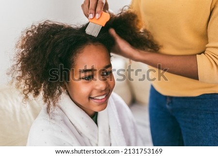 Mother doing head lice cleaning on her daughter curly hair. 