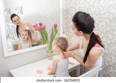 Mother Doing Her Little Daughter's Hair Near Mirror