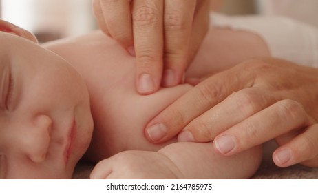 Mother Doing Massage On Her Healthy Sleeping Infant Baby. Small Caucasian Newborn Resting And Laying On His Belly While His Mother Is Performing A Massage For His Small Back And Developing Muscles. 
