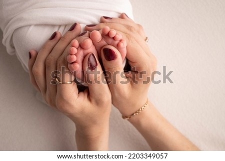 Mother is doing massage on her baby foot. Closeup baby feet in mother hands. Prevention of flat feet, development, muscle tone, dysplasia. Family, love, care, and health concepts. Studio macro. 