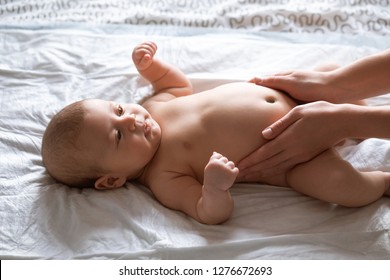 Mother Doing Tummy Massage To Newborn Baby. Mom Massaging Infant Belly, Baby Smiling. Treatment Of Colic