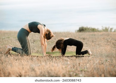Mother doing yoga with child girls over sea background together. Motherhood. Healthy lifestyle.