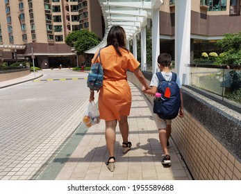 Mother Or Domestic Helper Picks Up Son Or Kid Of Primary School Student, Carrying School Bag Return Home In Afternoon, Walking Along Street In Hong Kong On Sunny Day