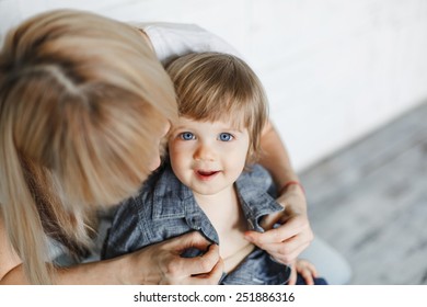 Mother Dressing Up Her One Year Old Blue Eyed Boy.