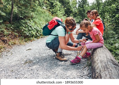 Mother dressing the wound on her little daughter's knee with medicine in spray. Accident happened during family summer vacation trip. People actively spending time