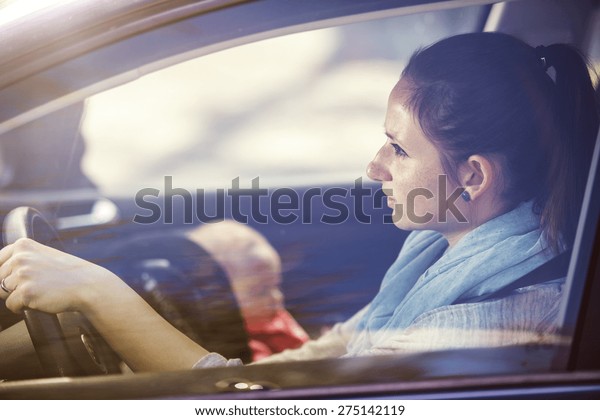 Mother driving a car, having her little baby girl in\
a child seat