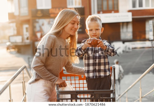 Mother is driving in a trolley. Family in a
parking near a
supermarket.
