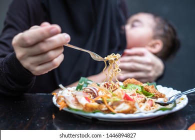 Mother eating spicy while baby sleep and breastfeeding in the restuarant. Baby in mother's hugging and breastfeeding while mother is eating.