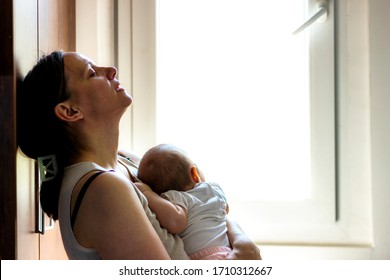 Mother embracing her baby girl while sleeping,lifestyle concept.Tired concerned mother rocking sleeping baby in kitchen.Portrait of young woman and cute little baby in home interior.Motherhood concept - Powered by Shutterstock